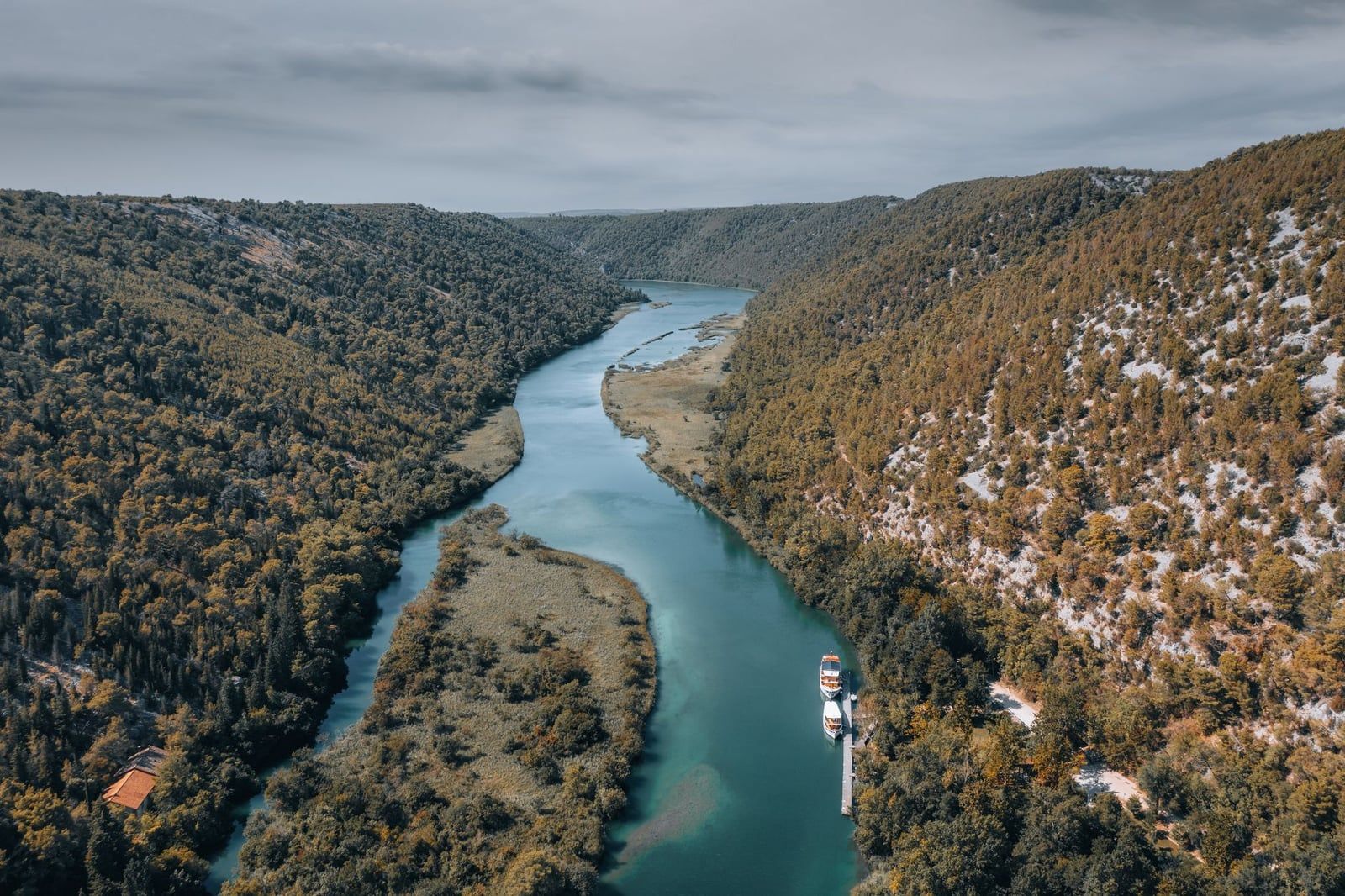 Vue aérienne de bateaux d'excursion amarrés le long du canyon boisé de la rivière Krka dans le parc national de Krka.