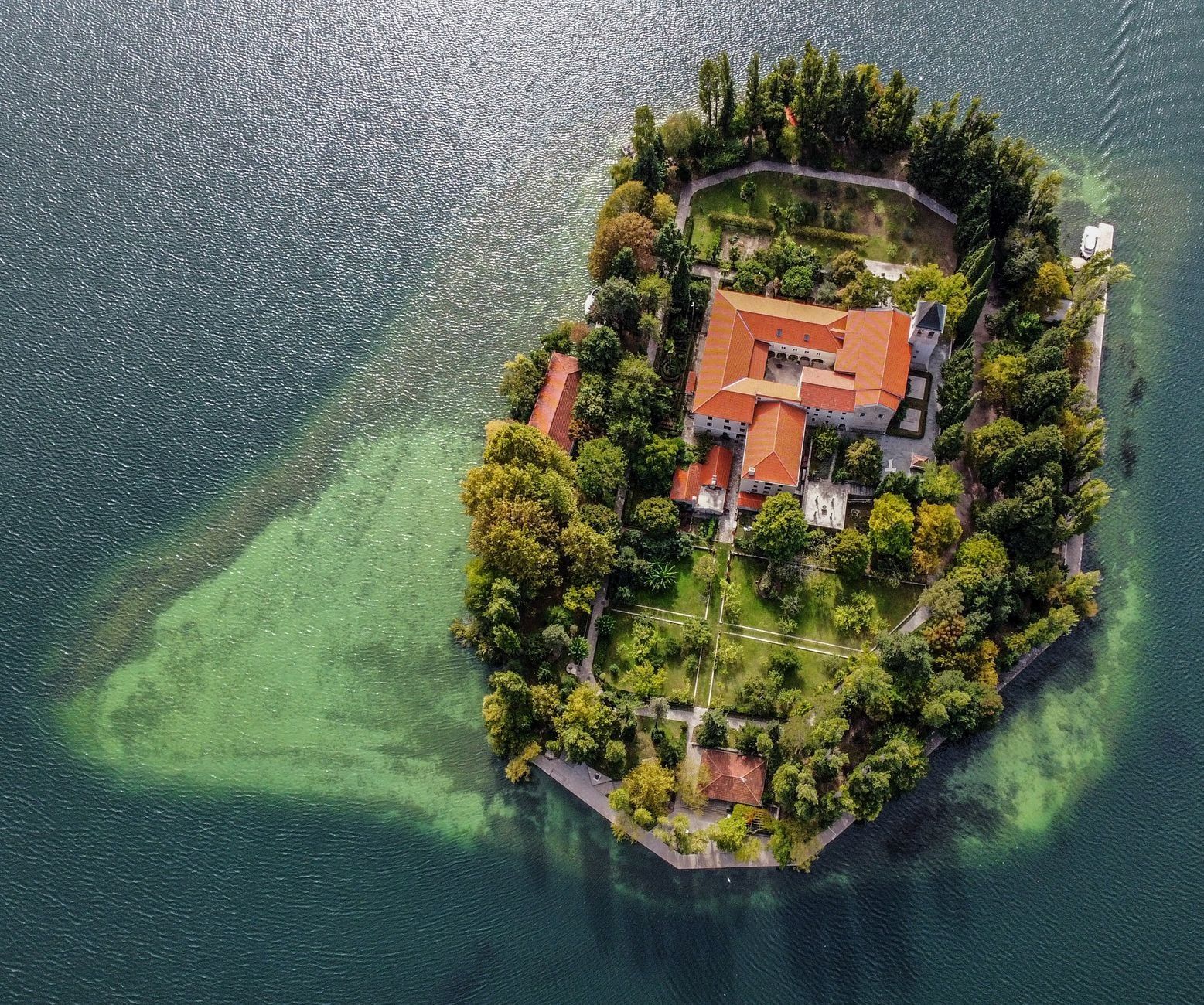 Aerial view of the Franciscan monastery and gardens on Visovac Island, surrounded by clear waters in Krka National Park.