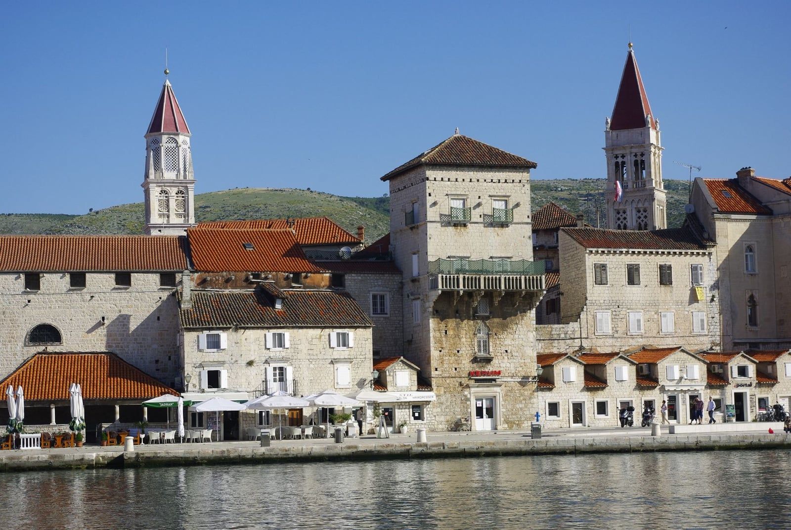 Historic stone buildings and church bell towers line the waterfront of Trogir's old town, an ideal starting point for day trips to Krka National Park.